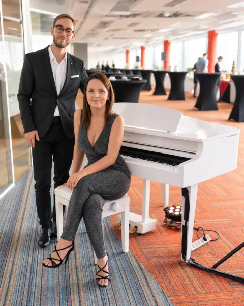 Roksana Wierzbicka z pianistą przy białym fortepianie na evencie firmowym