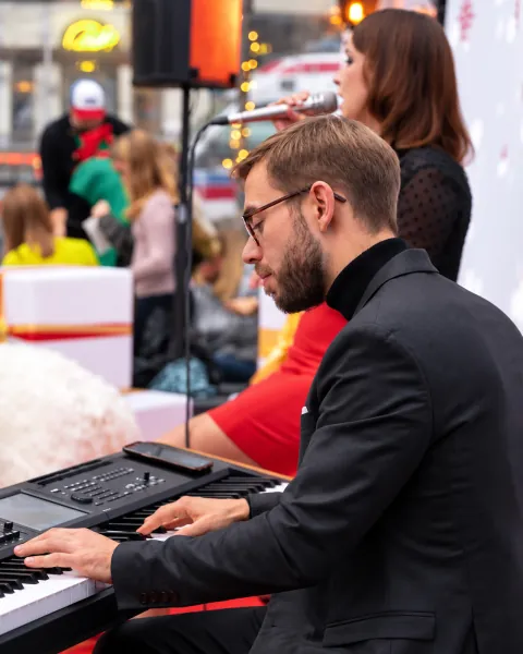 Pianista przy klawiszach, w tle Roksana Wierzbicka śpiewa świąteczny repertuar